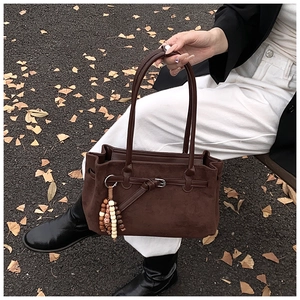 Detail of dark brown matte tote bag featuring vintage belt knots and wooden bead tassels