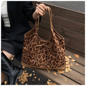 Detail of leopard print tote bag with bow accent on a wooden bench in autumn setting