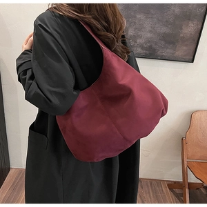 Detail view of burgundy faux suede hobo shoulder bag shown on a model for autumn style