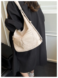 Detail of cream hobo bag with multiple pockets and adjustable strap shown on model
