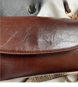Close-up of deep brown leather bag showing gold brand logo and rich natural texture
