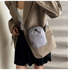 Detail of grey nylon crossbody phone bag with drawstring and texture on model outfit