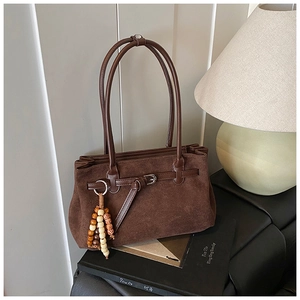 Detail of dark brown suede tote bag with vintage strap buckle and beaded tassel charm