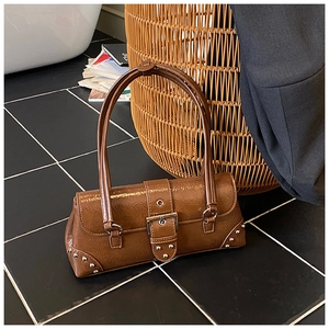 Detail of vintage brown shoulder bag with metallic studs and buckle on black floor