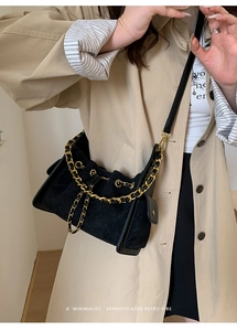 Détail des coutures matelassées et chaîne dorée sur le sac seau en cuir noir mat