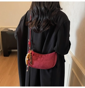 Detail of burgundy matte half-moon shoulder bag featuring a beaded tassel and knot detail