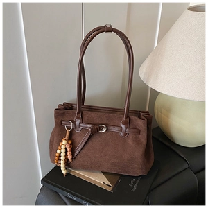 Close-up of dark brown suede tote featuring metal buckle and ethnic bead charm detail