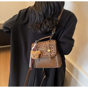Detail of leopard print patchwork crossbody bag with plush bear charm and leather label