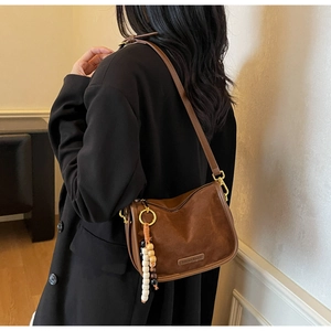 Detail of vintage brown suede shoulder bag with retro beaded charms and golden hardware
