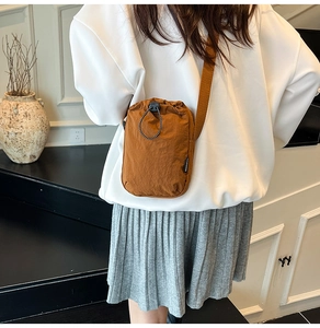 Detail of caramel nylon crossbody phone bag with drawstring closure and fashion label