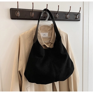 Detail of minimalist black hobo bag with textured suede finish and stitched construction