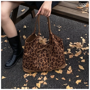 Street style shot of a leopard print tote bag with brown leather trim and bow detail