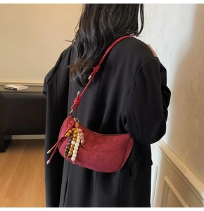 Detail of burgundy frosted suede crescent bag with ethnic colorful wood bead charm
