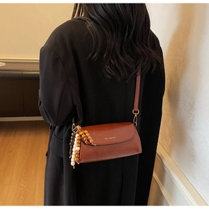 Detail of vintage brown leather crossbody bag featuring colorful wood bead tassels