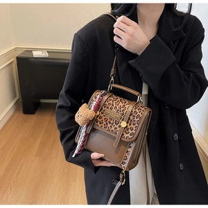 Detail of leopard print crossbody bag with plush bear charm and silk scarf on black blazer