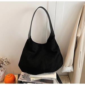 Detail of minimalist black suede tote bag with leather straps on lifestyle backdrop