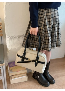 Chic cream suede Boston bag with black leather handles shown held by a model