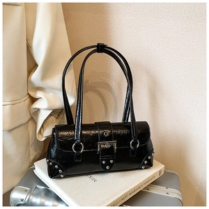 Macro detail of black crinkle patent leather texture and silver buckle on shoulder bag