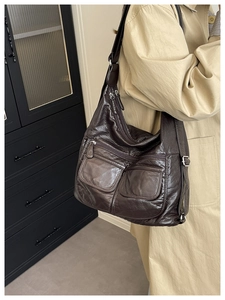 Close-up of vintage brown leather bag with multi-pocket details and glossy texture