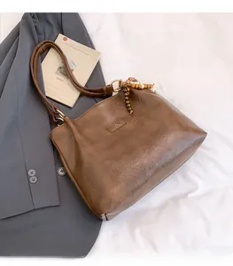 Close-up of brown faux leather tote bag featuring a wooden beaded charm and fine texture