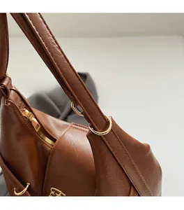 Gros plan sur la texture du cuir marron avec des détails en métal doré sur le sac cabas