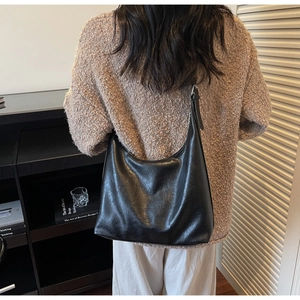 Detail of adjustable leather strap and slouchy silhouette of the black tote bag