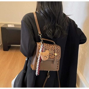 Detail of leopard print crossbody bag with bear charm and woven strap on model back