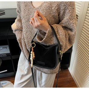 Détail du sac bandoulière noir avec finition mate et pendentif ethnique en bois