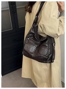 Detailed view of brown lychee leather shoulder bag with side pockets on female model