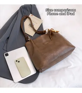 Size comparison of brown leather tote bag with iPad and smartphone for reference