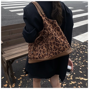 Outdoor street style shot of a large leopard print tote bag with brown leather trim