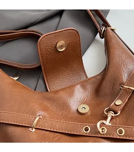 Détail du fermoir magnétique et de la bandoulière réglable du sac cabas en cuir marron