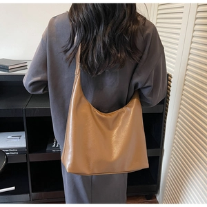 Detailed close-up of brown leather tote bag showing smooth texture and large capacity