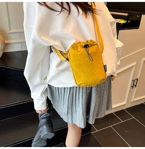 Detail of yellow nylon drawstring crossbody bag with fashion label on adjustable strap
