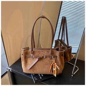 Detail of brown faux suede tote with metallic buckle and wooden beaded charm accent