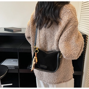 Détail du sac demi-lune en daim noir avec fermeture éclair et perles en bois