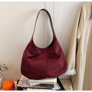 Detail of burgundy suede hobo bag featuring vertical stitching and a semi-moon shape