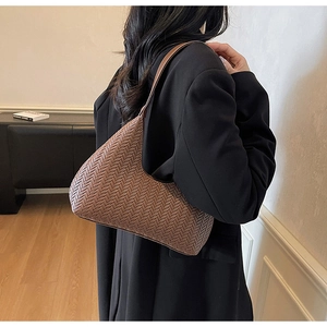 Dettaglio della texture in pelle intrecciata di una borsa sottobraccio a mezzaluna marrone
