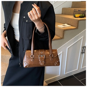 Detail of vintage brown patent leather baguette bag with silver rivets and buckle