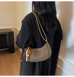 Detail of olive brown suede half-moon shoulder bag with colorful ethnic beaded charm