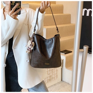 Detail of dark brown leather tote bag with leopard print bear pendant on the strap
