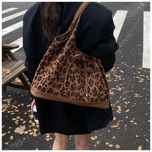 Close-up of leopard print tote bag with brown leather trim and bow tie detail