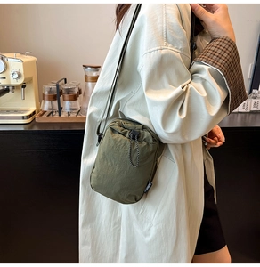 Close-up of military green nylon crossbody bag with fashion label and drawstring detail