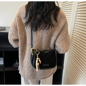 Sac bandoulière noir mat avec perles en bois vintage porté par un mannequin