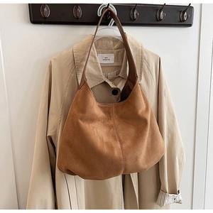 Detail of caramel brown suede tote bag with vertical stitching on soft hobo shape
