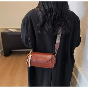 Detail of vintage brown leather crossbody bag with geometric jacquard strap and beads