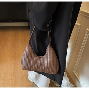 Dettaglio della trama intrecciata marrone su una borsa hobo con motivo a spina di pesce