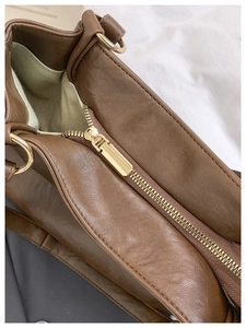 Detailed close-up of premium brown leather tote zipper with golden metal hardware