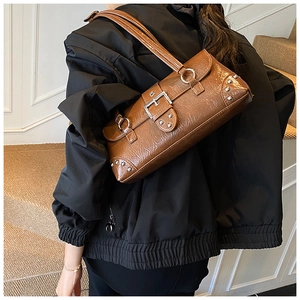 Detail view of retro brown shoulder bag featuring silver rivets and industrial buckles