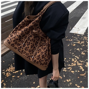 Outdoor street shot of large leopard print tote bag with brown leather straps and drawstring